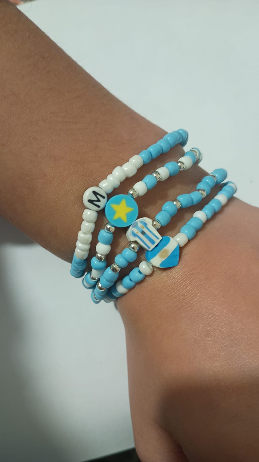 Pulseras celestes y blancas con dijes de estrella, camiseta y bandera argentina